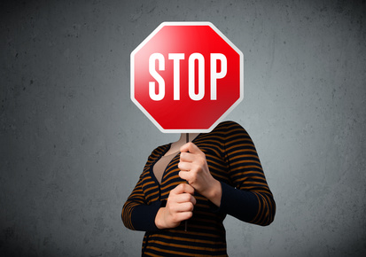 Young lady standing and holding a stop sign in front of her head
