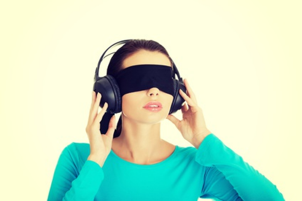 Woman who is blindfolded and listening to headphones