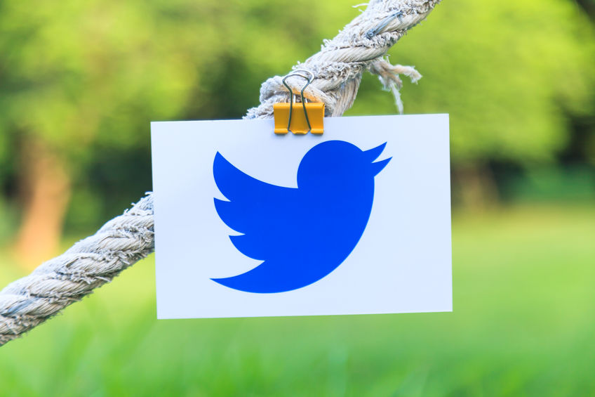 Twitter logo sign printed on paper hanging on a rope in the park. Twitter is an online social networking popular social media.
