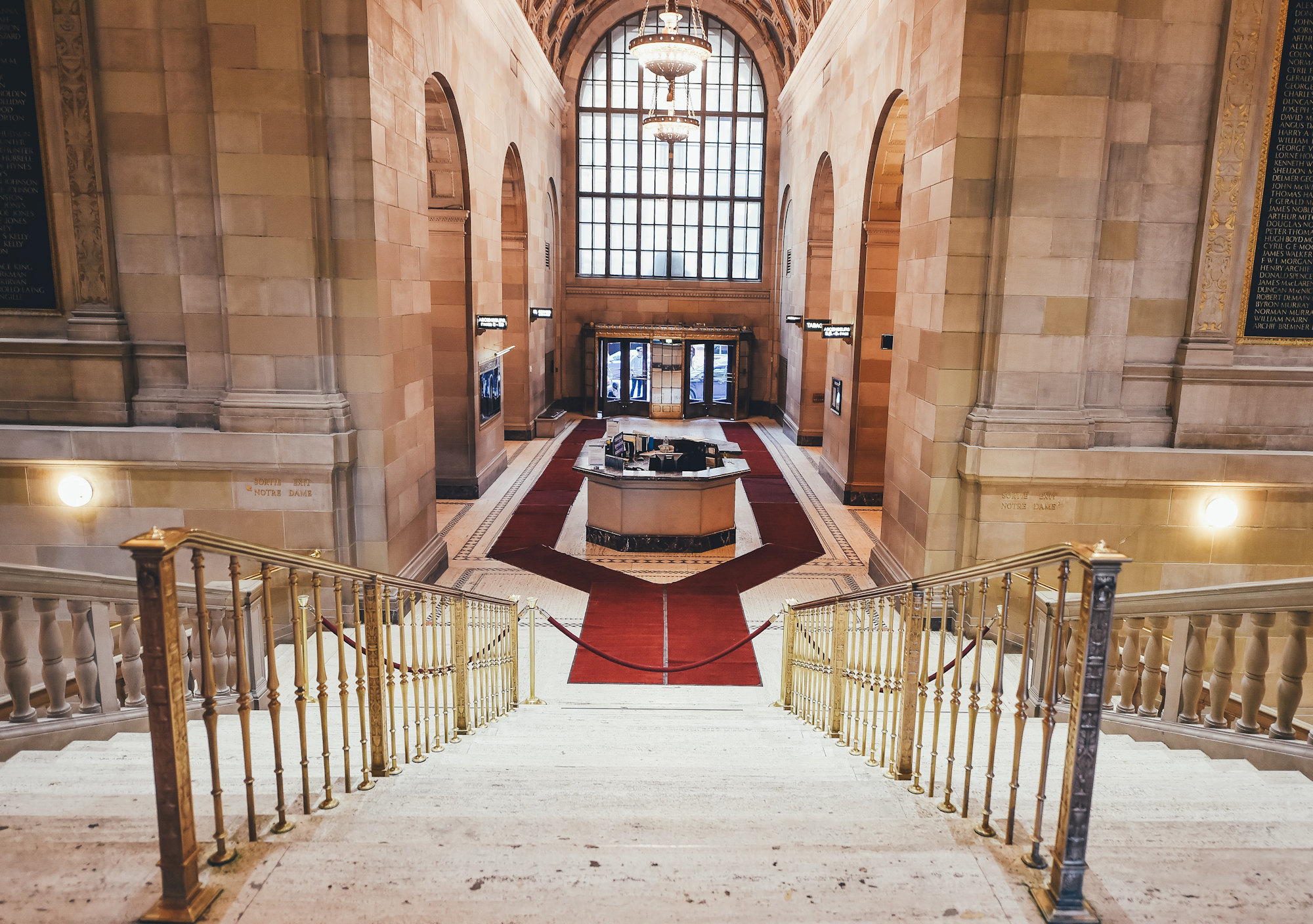 View down the stairs of a fancy building, ending in a velvet rope