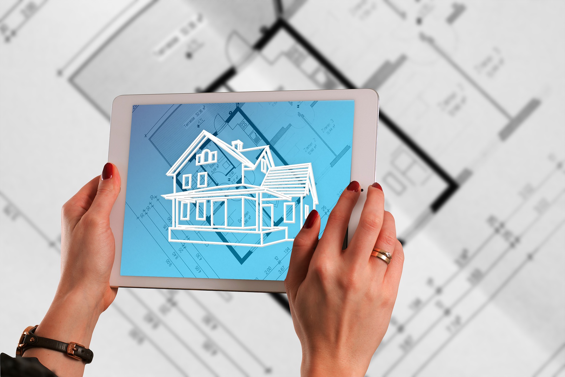 Augmented reality house appearing on tablet held over blueprints